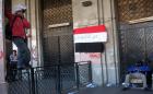 An Egyptian protester stands on a gate in front a national flag on which is written in Arabic "Egypt is moor safe without Muslim Brotherhoods’’ in front of the Mugamma, Cairo's main administrative building on February 24, 2013 part of a growing campaign of civil disobedience around the country. (AFP)